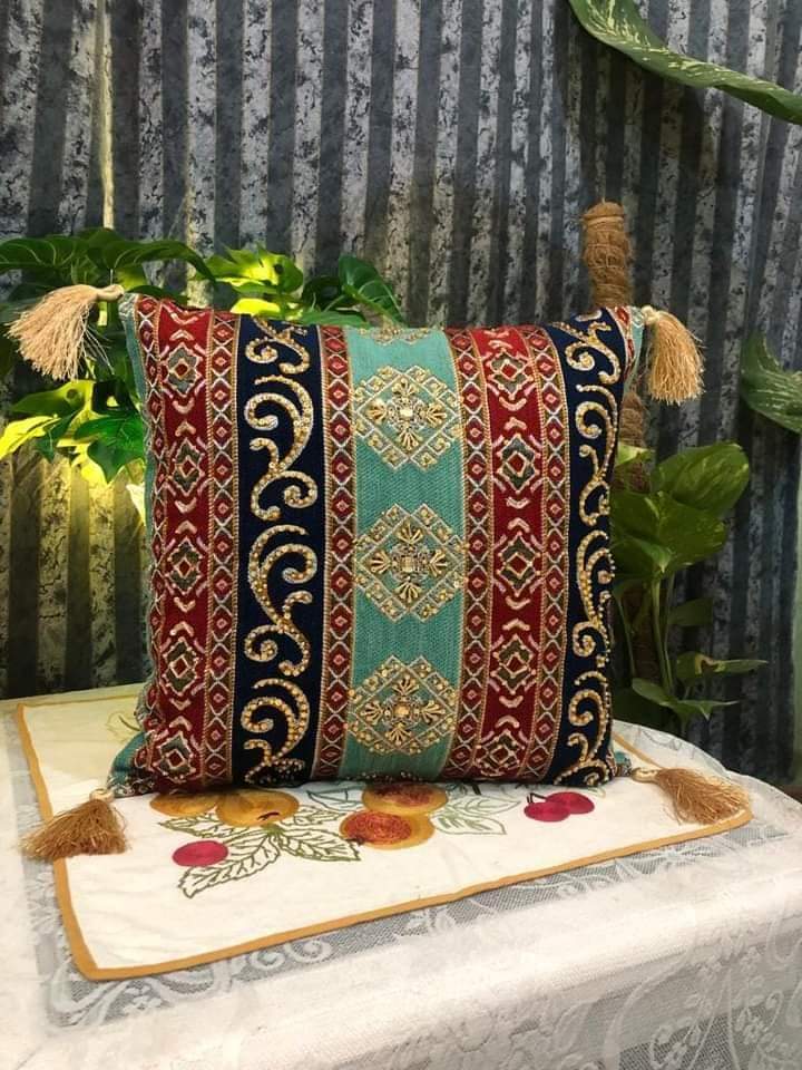 Hand-embroidered cushion covers with sequins, beads, gold ruffles, and tassels.