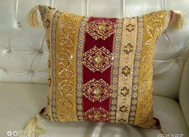 Hand-embroidered cushion covers with sequins, beads, gold ruffles, and tassels.