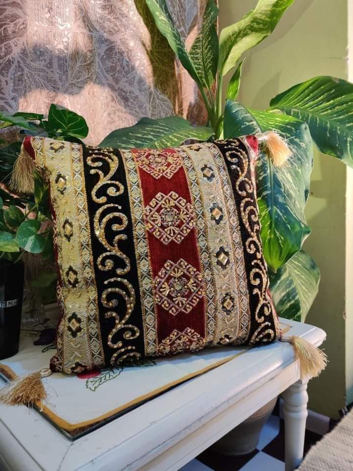 Hand-embroidered cushion covers with sequins, beads, gold ruffles, and tassels.