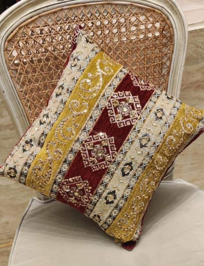 Hand-embroidered cushion covers with sequins, beads, gold ruffles, and tassels.