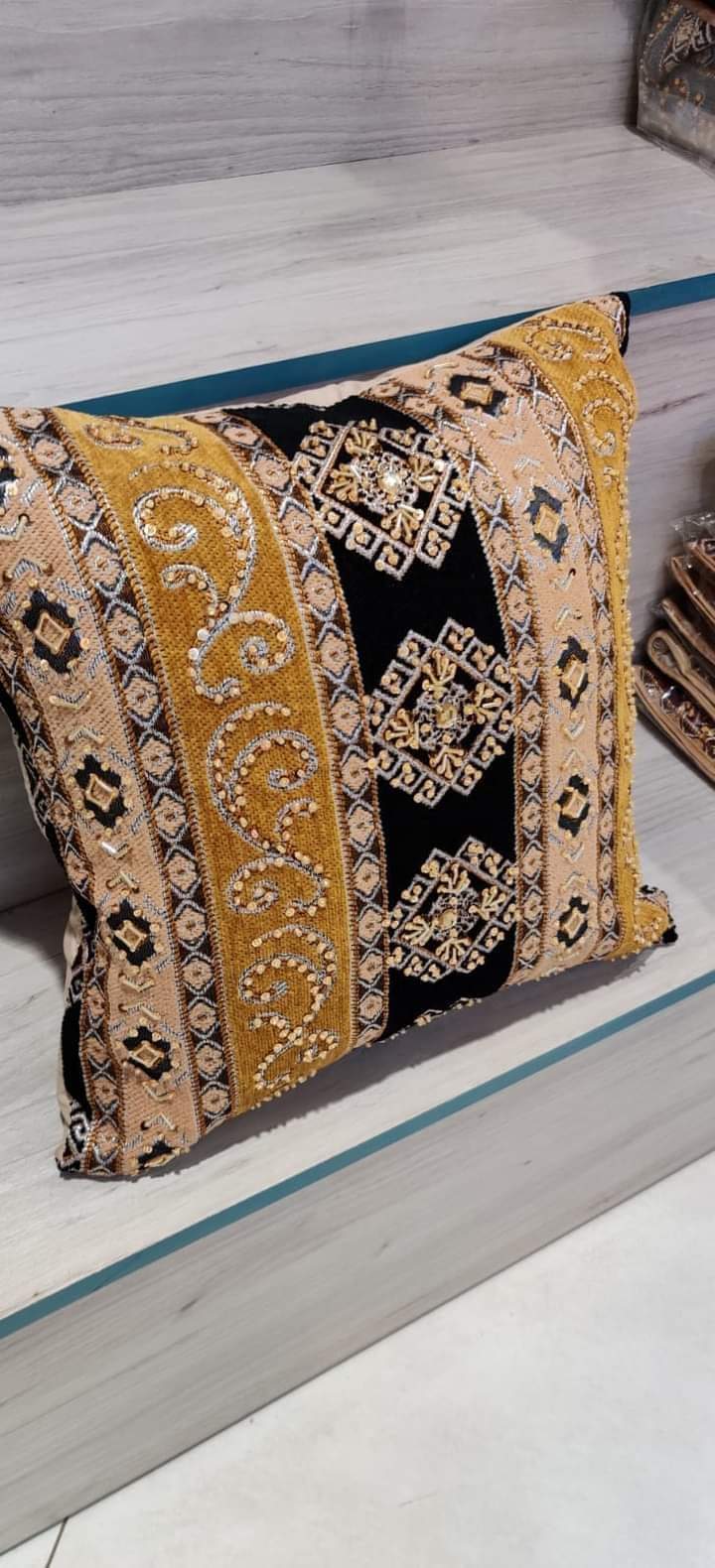 Hand-embroidered cushion covers with sequins, beads, gold ruffles, and tassels.